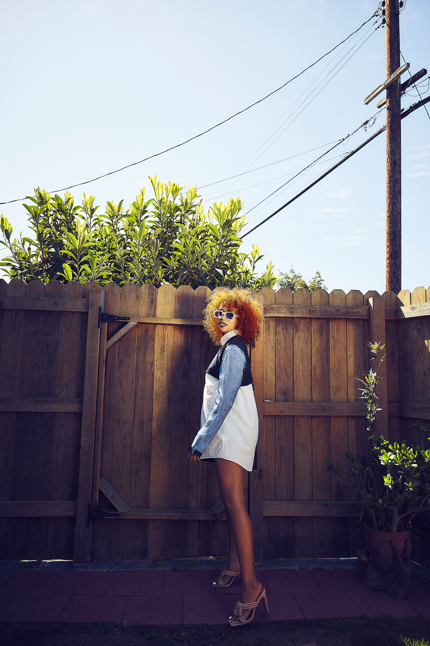 The model poses in a Modern Abstract Shirt against a wooden backdrop, emphasizing its architectural look. This piece is a great example of elegant African dresses for ladies and represents trendy African wear for women.