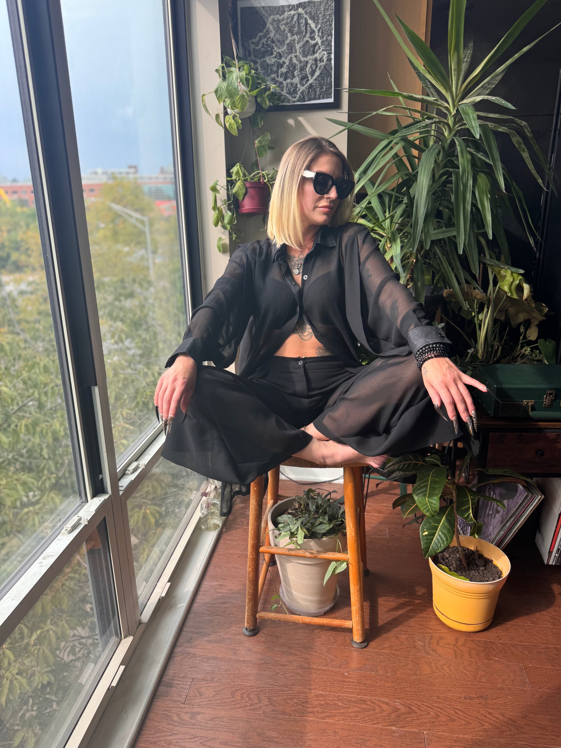 A woman sitting in relaxation while wearing a Matching Set- Kaftan Top, presenting a stylish black matching kaftan set African outfit. This modern african two piece set includes a sheer kaftan and chic pants, perfect for showcasing trendy african women attire. The outfit celebrates the elements of traditional african suit design, capturing the essence of west african fashion, and is an ideal addition to any wardrobe of african kaftan dresses for ladies.