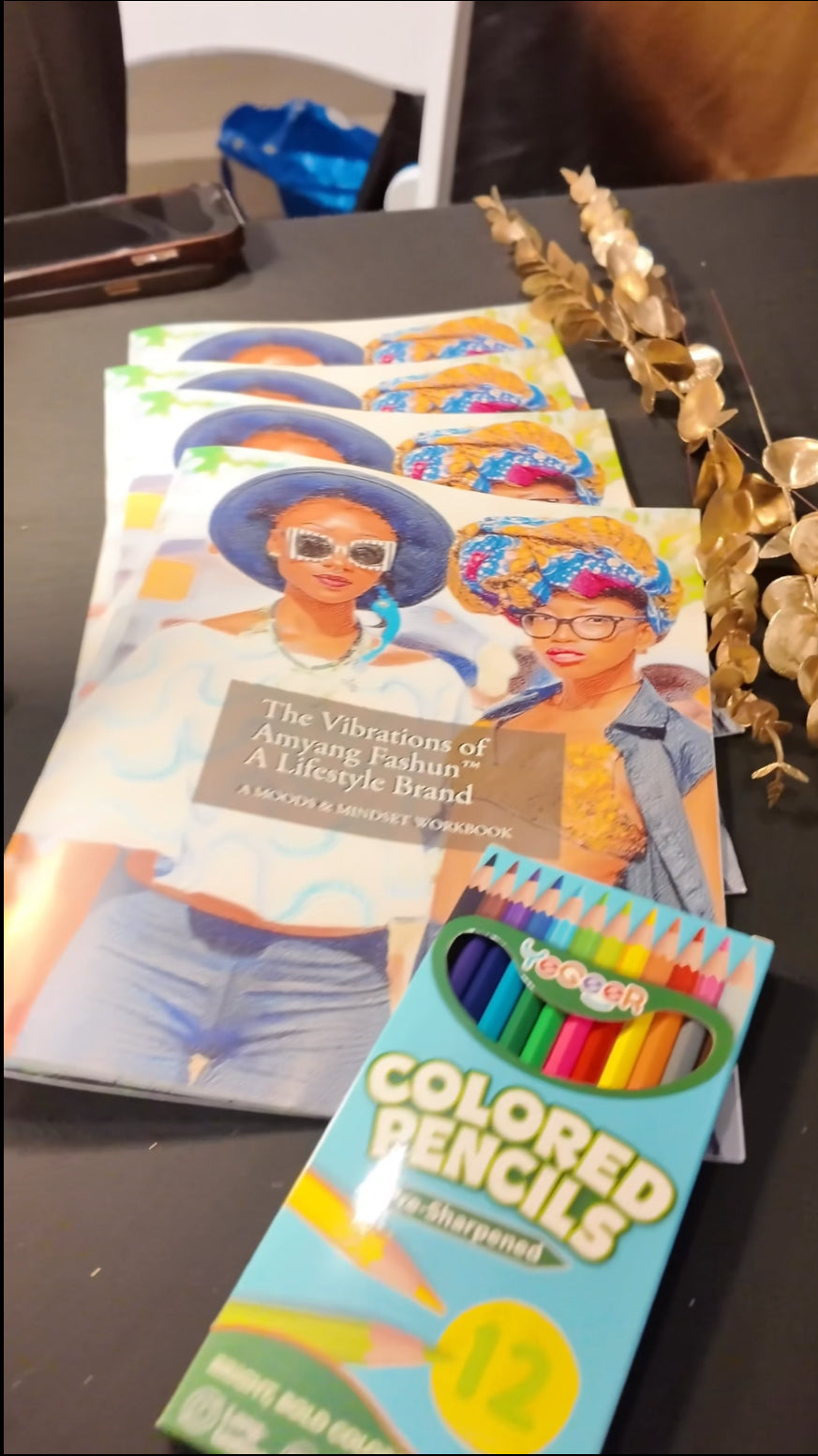 The Vibrations of Amyang Fashun™ A Lifestyle Brand: VOLUME I featuring a colorful display of the MINDSET WORKBOOK SERIES with intentional self-care alongside colored pencils.