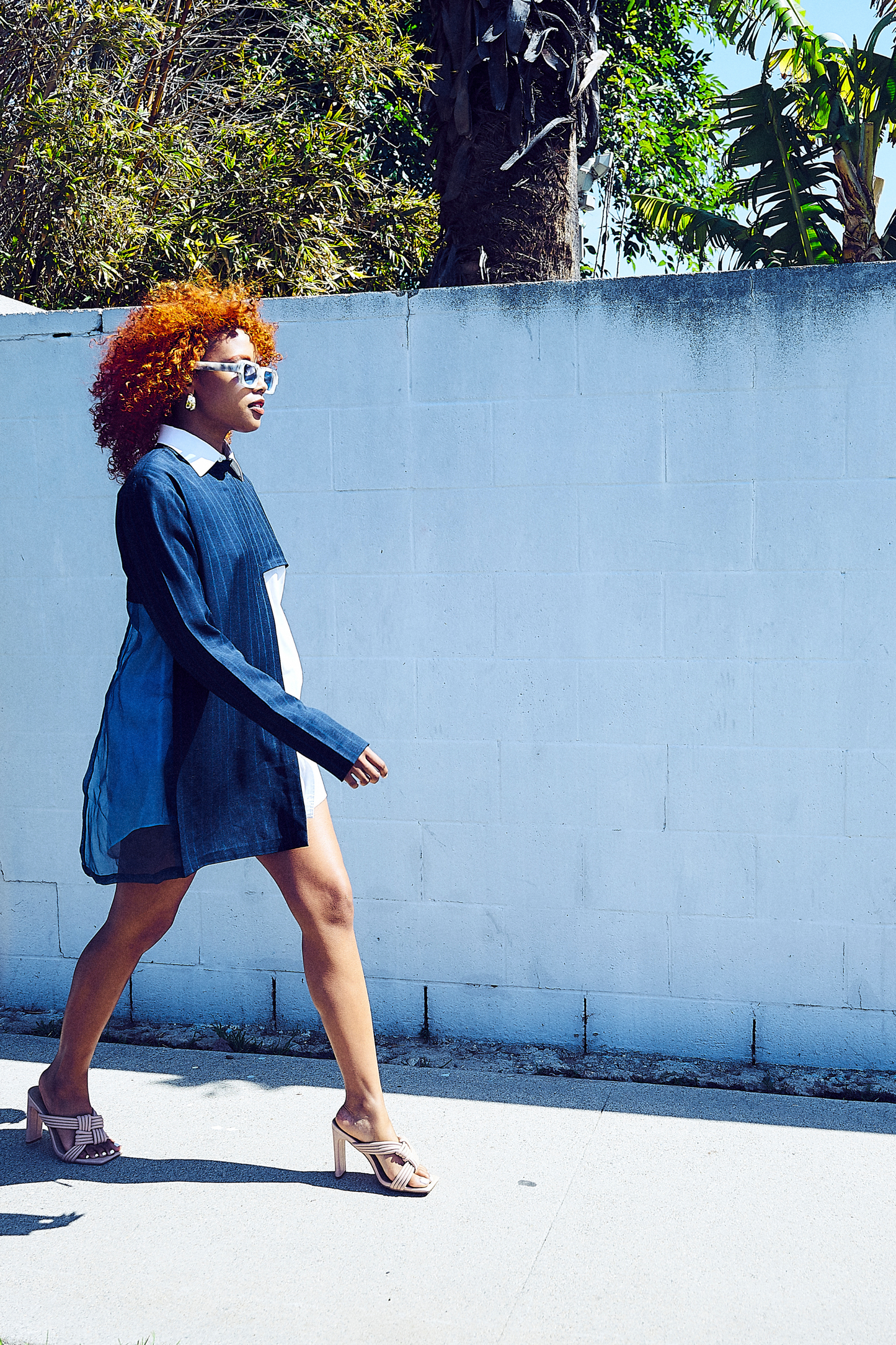 A woman confidently strides in a Modern Abstract Shirt, embodying an architectural look complemented by elegant touches. This attire represents fashionable African wear for women and is ideal for stylish African dress styles for women.