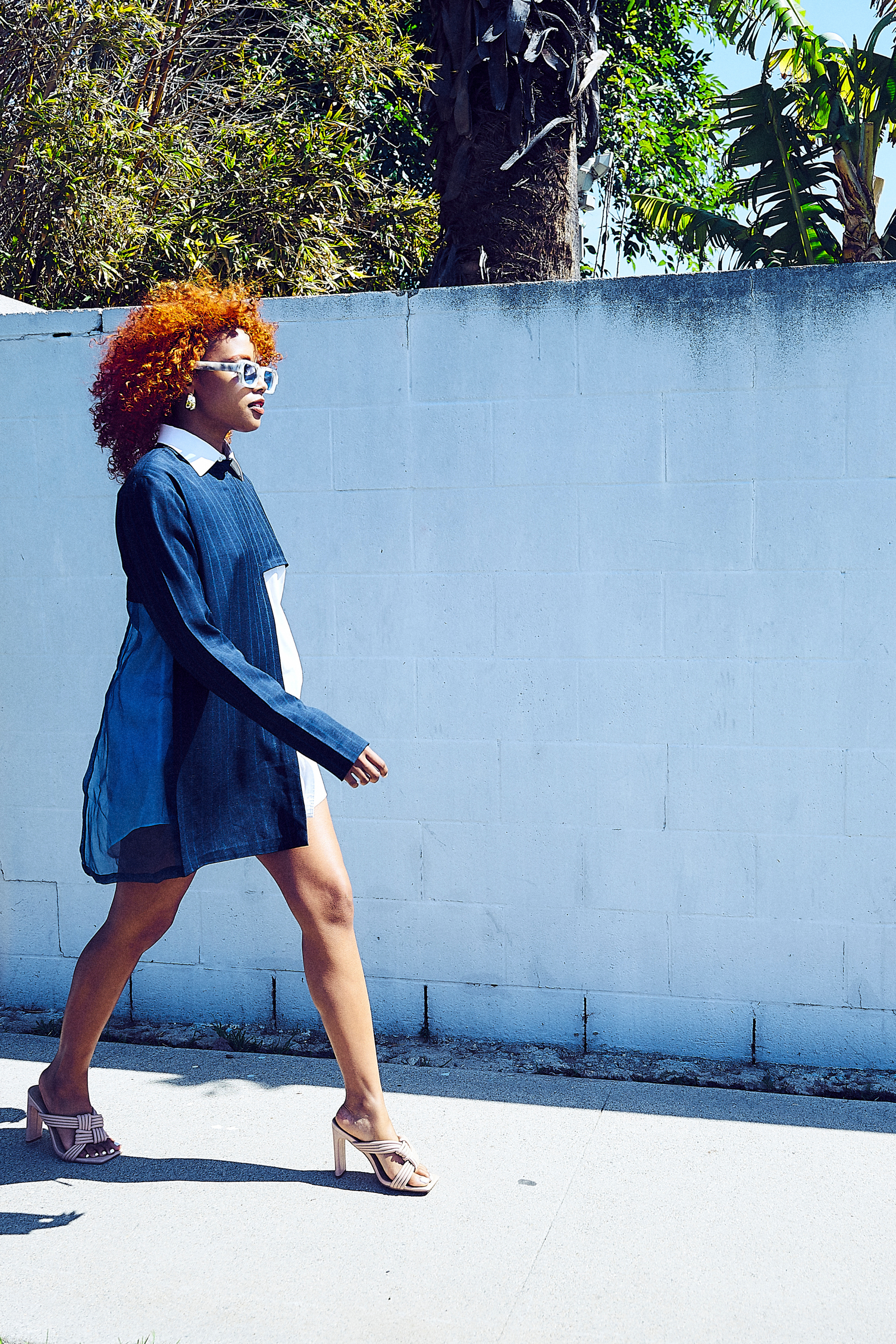 A woman confidently strides in a Modern Abstract Shirt, embodying an architectural look complemented by elegant touches. This attire represents fashionable African wear for women and is ideal for stylish African dress styles for women.