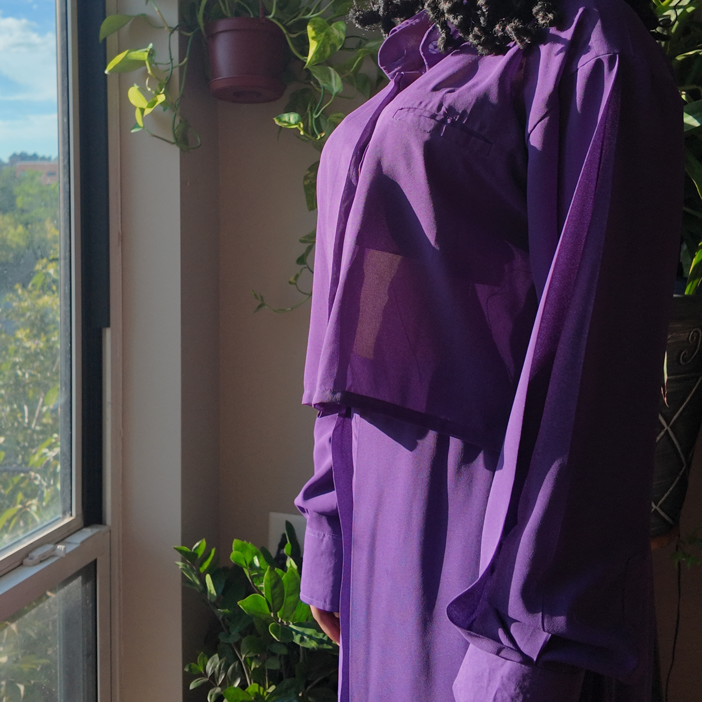 Another view of the Versatile Translucent Blouse in purple, beautifully showcasing its sheer design in a sunlit setting. This blouse is a trendy option within women's African clothing, appealing to those who love unique African apparel from esteemed African clothing brands.